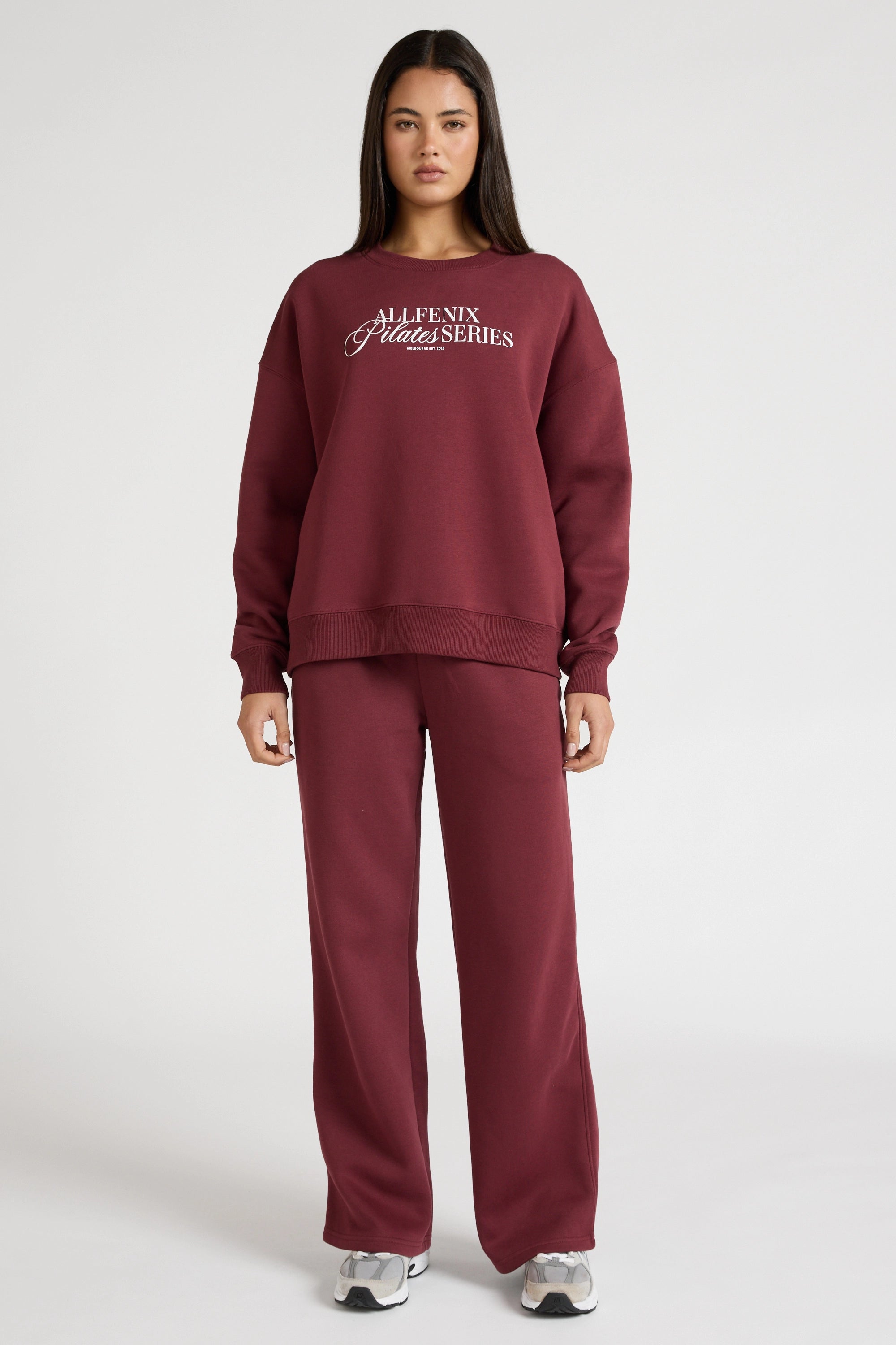 Woman wearing a maroon sweatshirt with 'All Fenix Pilates Series' text on a white background