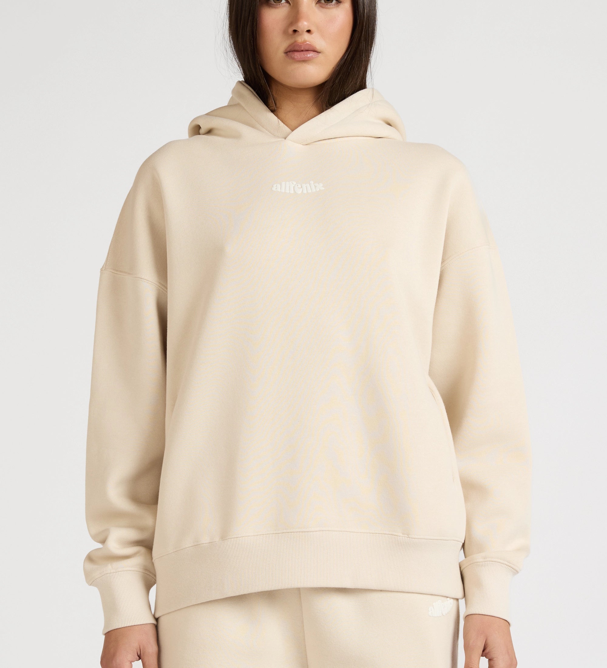 Woman wearing a beige hoodie and pants on a white background