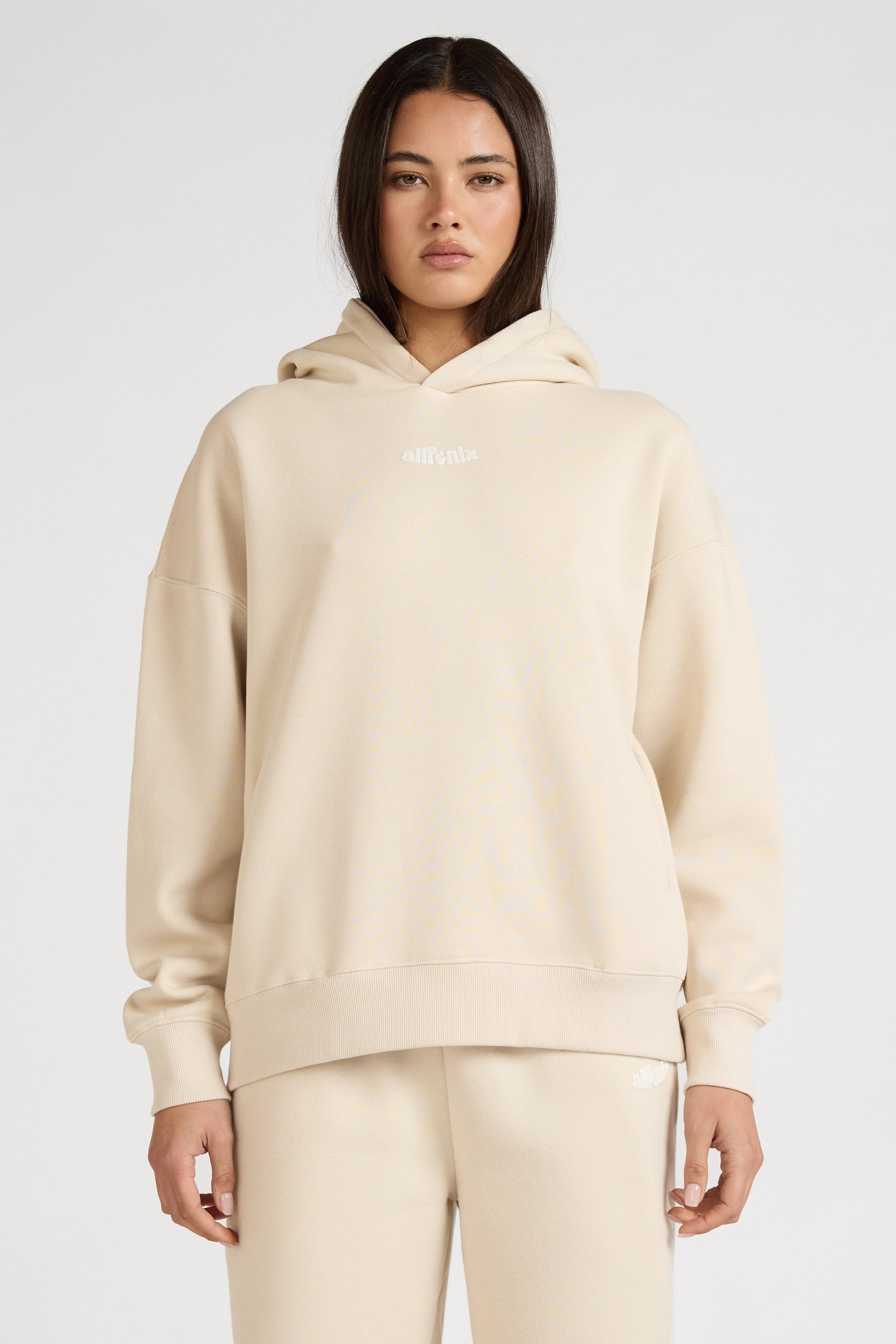 Woman wearing a beige hoodie and pants on a white background