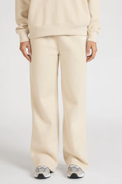 Woman wearing a clay beige tracksuit set with wide leg track pants on a white background