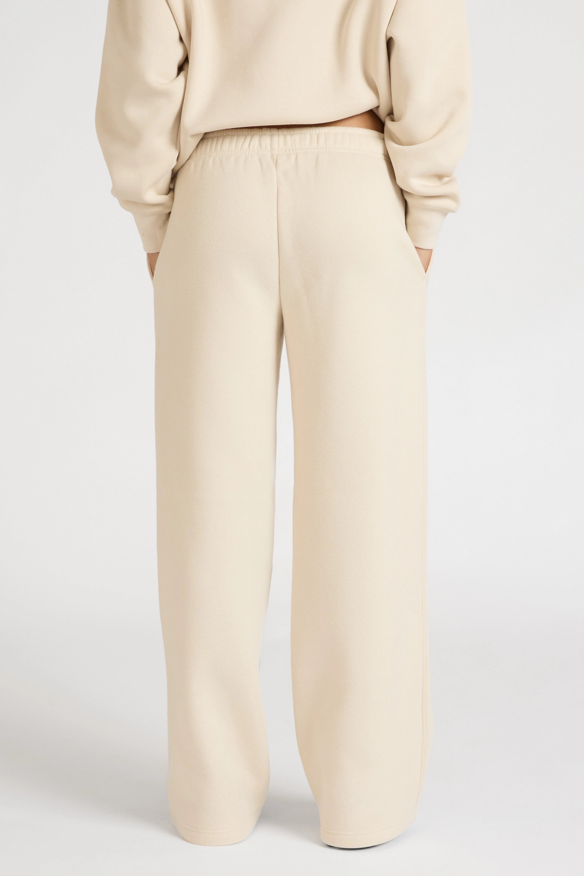 Woman wearing a clay beige tracksuit set with wide leg track pants on a white background