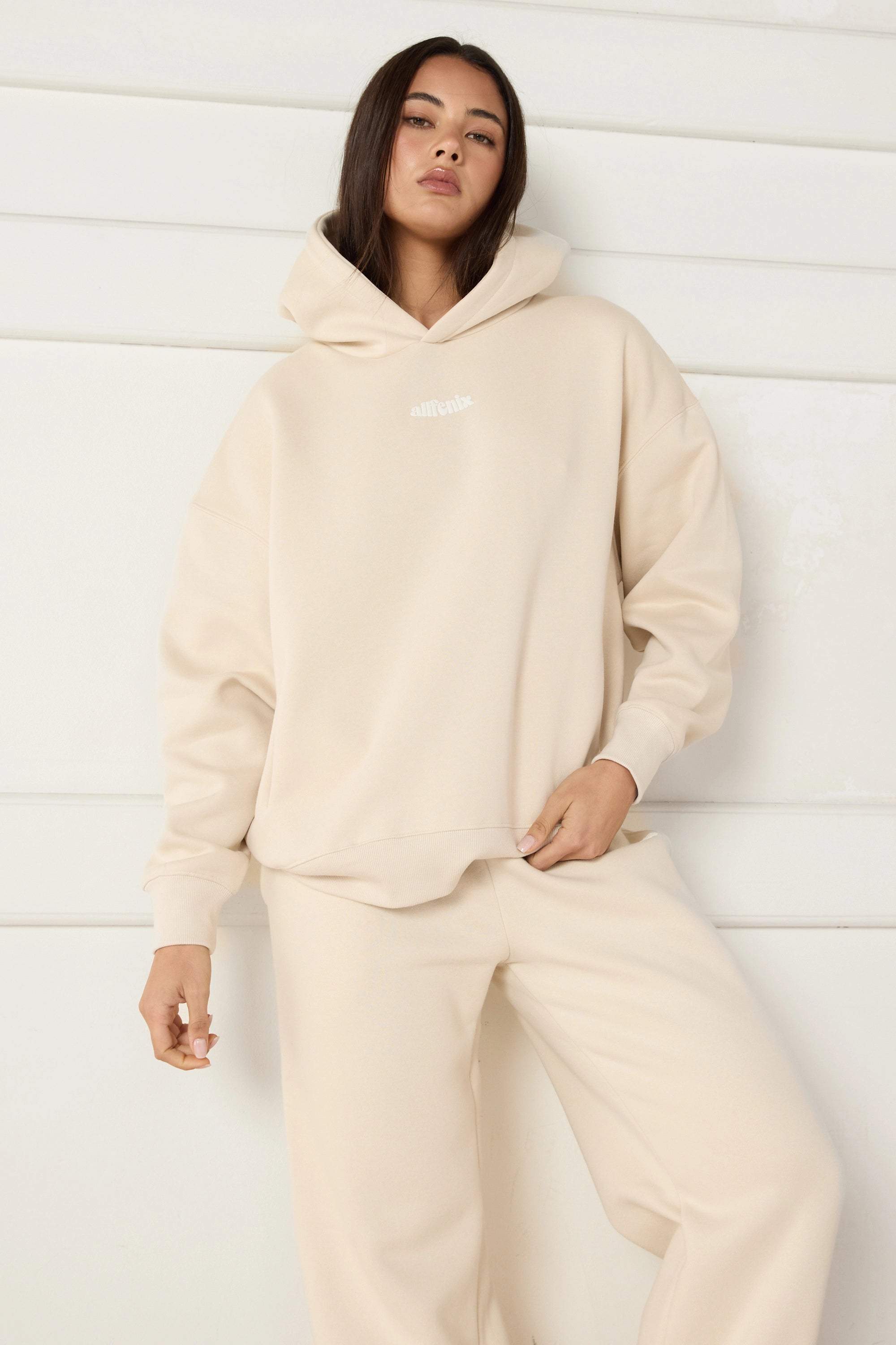 Woman wearing a beige hoodie and pants against a white background