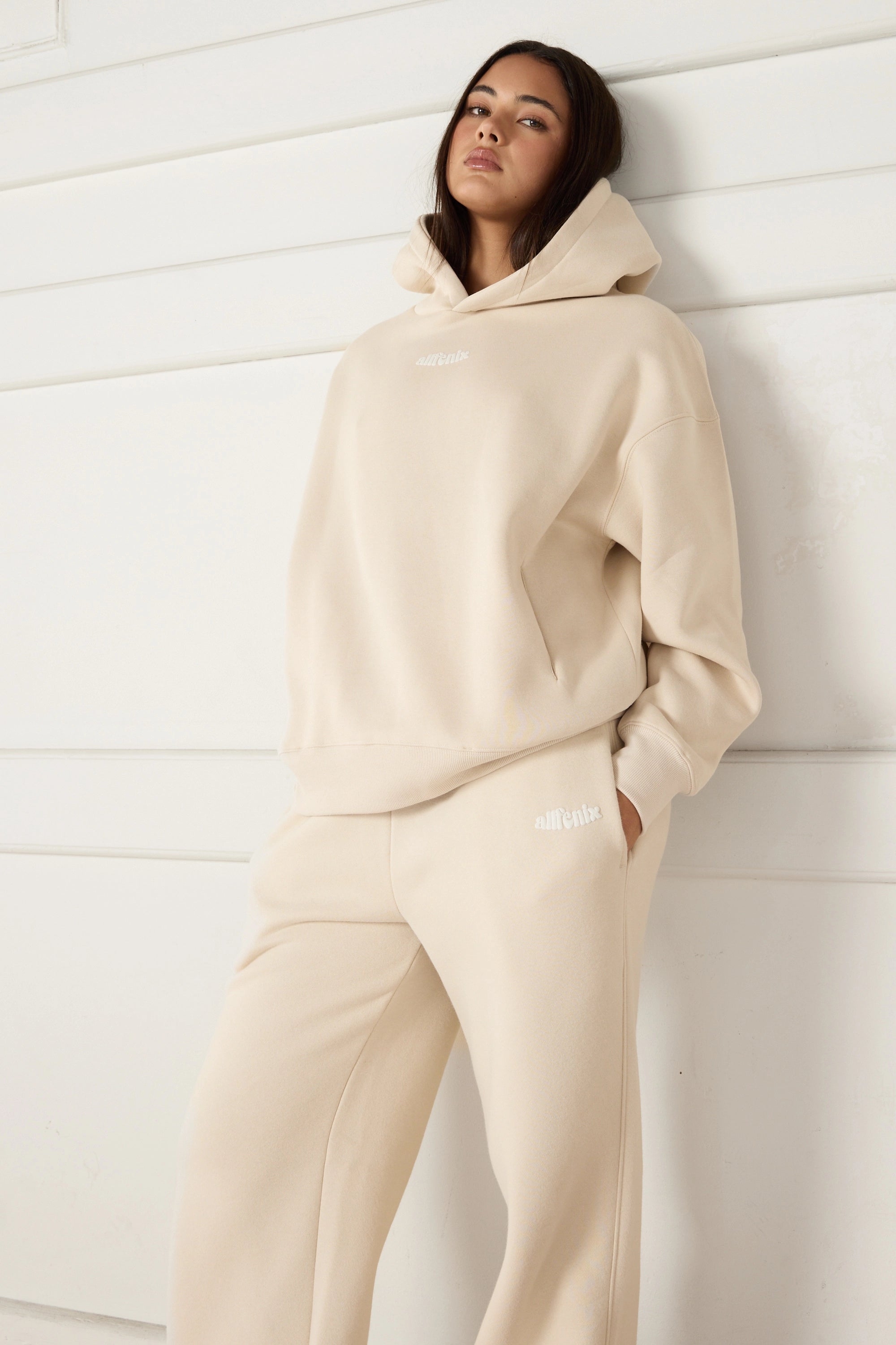 Woman wearing a beige tracksuit against a white background