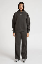 Woman wearing a dark grey hoodie and pants on a white background