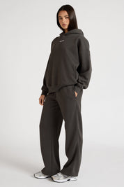 Woman wearing a dark grey hoodie and pants on a white background