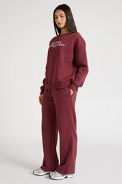 Woman wearing a maroon sweatshirt with 'All Fenix Pilates Series' text on a white background