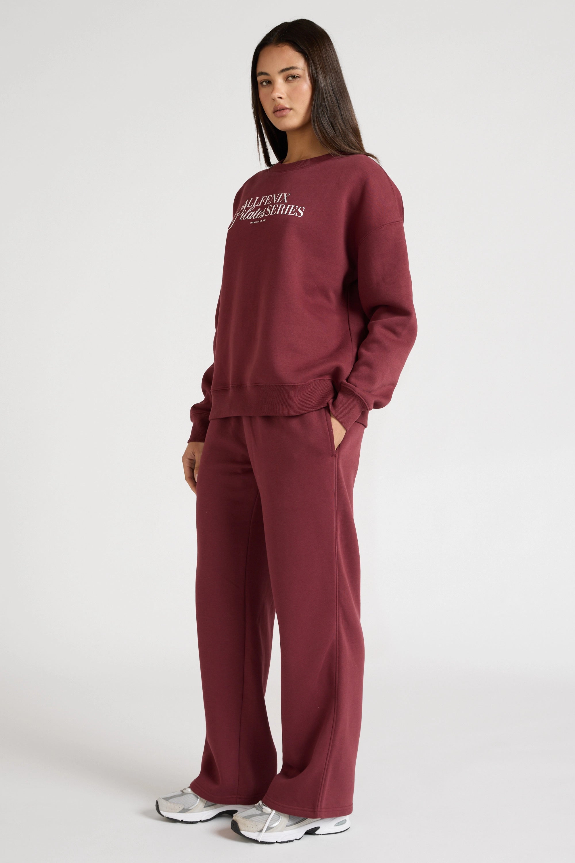 Woman wearing a maroon sweatshirt with 'All Fenix Pilates Series' text on a white background