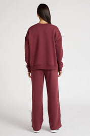 Woman wearing a maroon sweatshirt with 'All Fenix Pilates Series' text on a white background