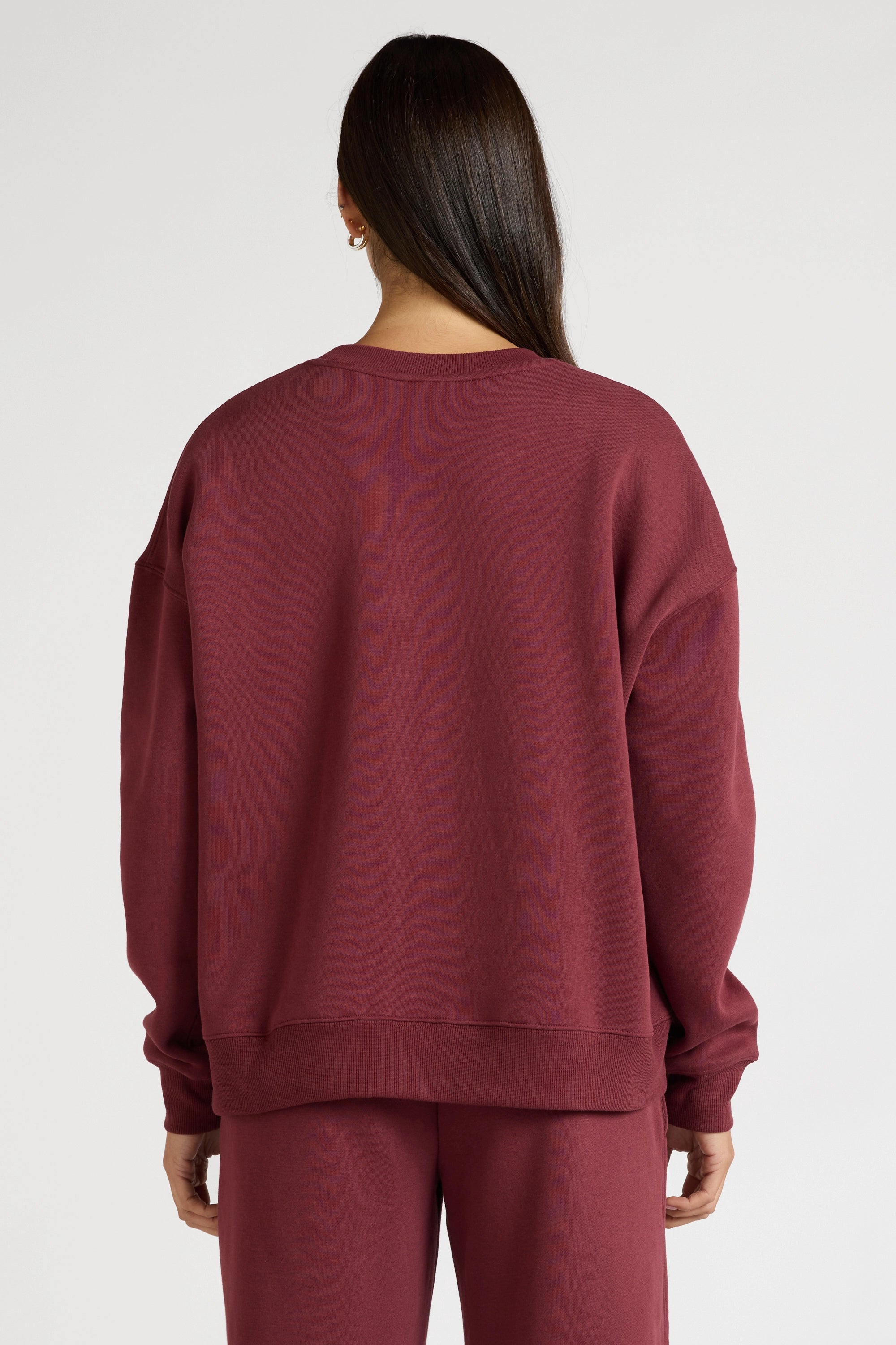 Woman wearing a maroon sweatshirt with 'All Fenix Pilates Series' text on a white background