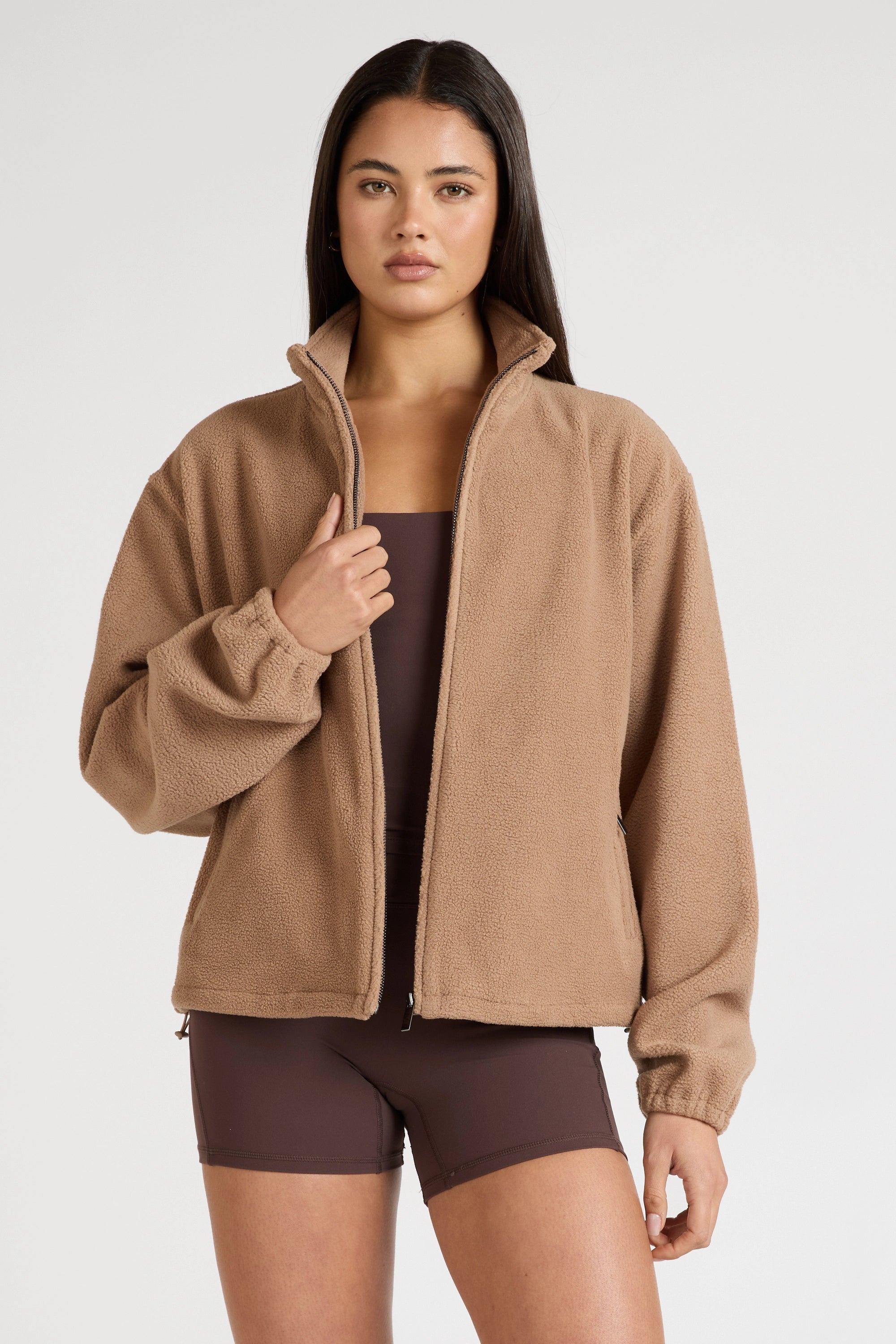 Woman wearing a brown fleece jacket on a white background